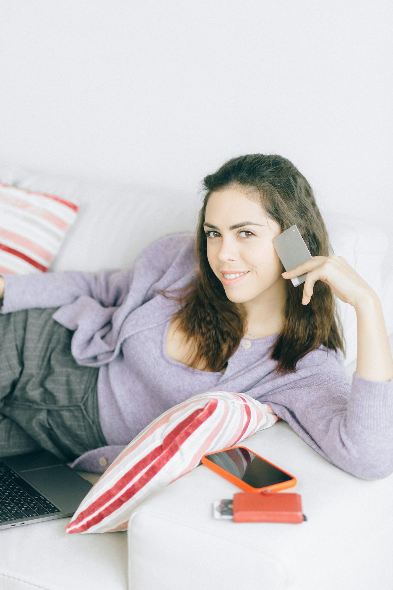 Relaxed woman using smartphone and laptop for online shopping at home.